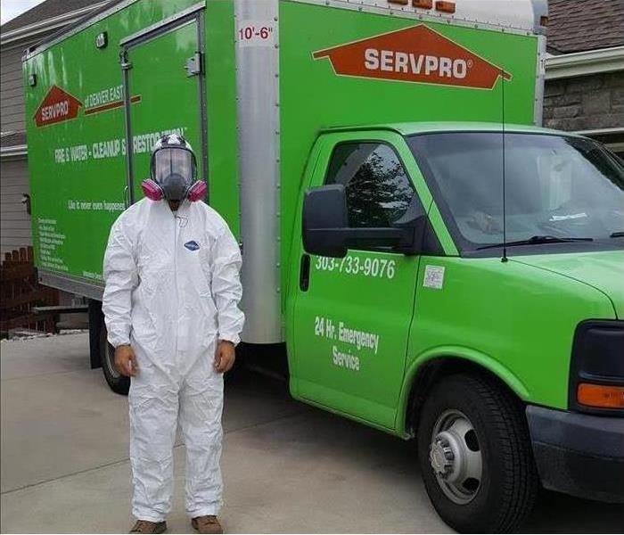 A man standing beside a green truck box wearing protective gear