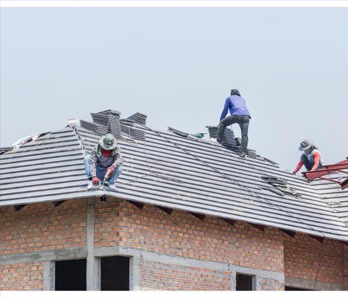 Workers installing concrete tiles on the roof